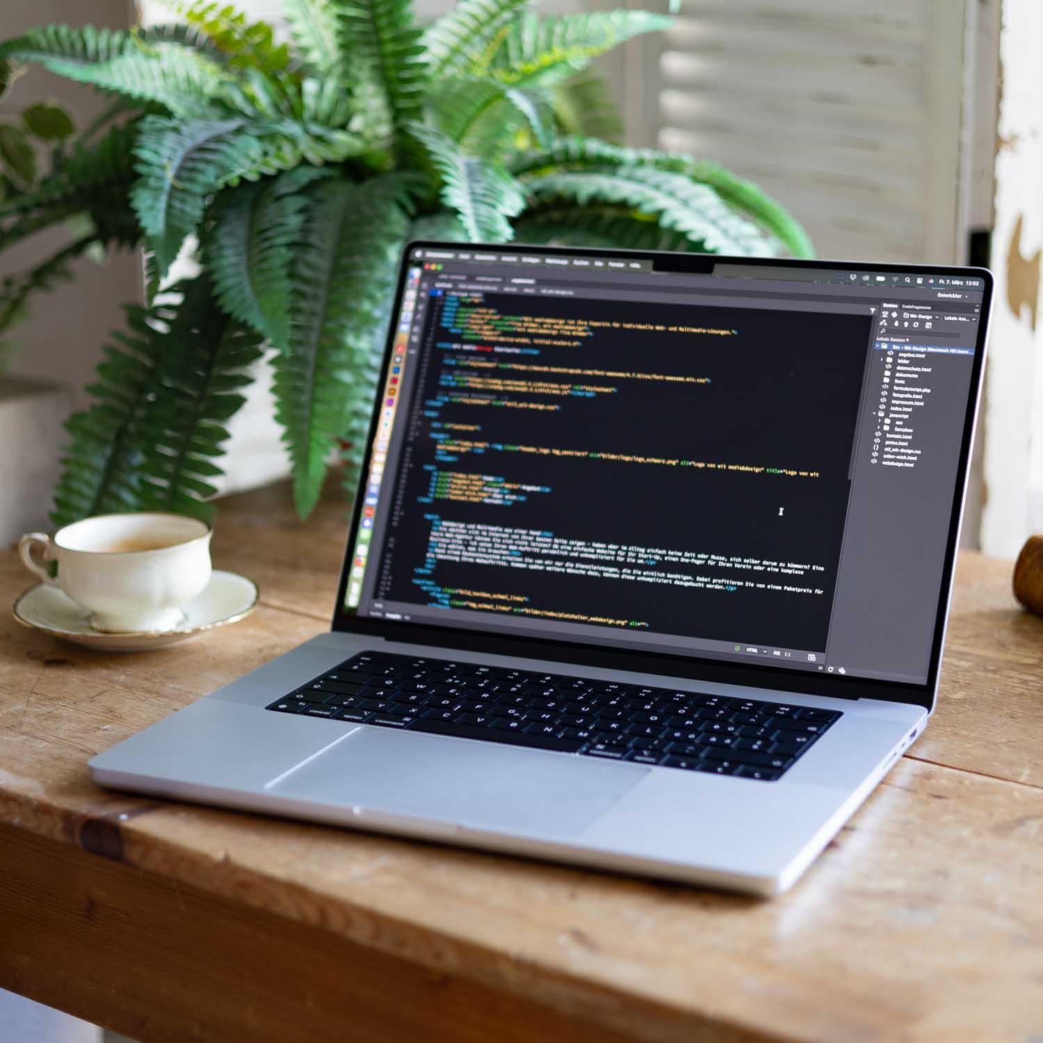 Macbook mit HTML-Code auf Holztisch